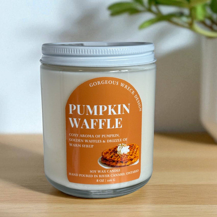 A 6 oz soy wax candle in a clear glass jar with a white lid, featuring an orange label that reads &