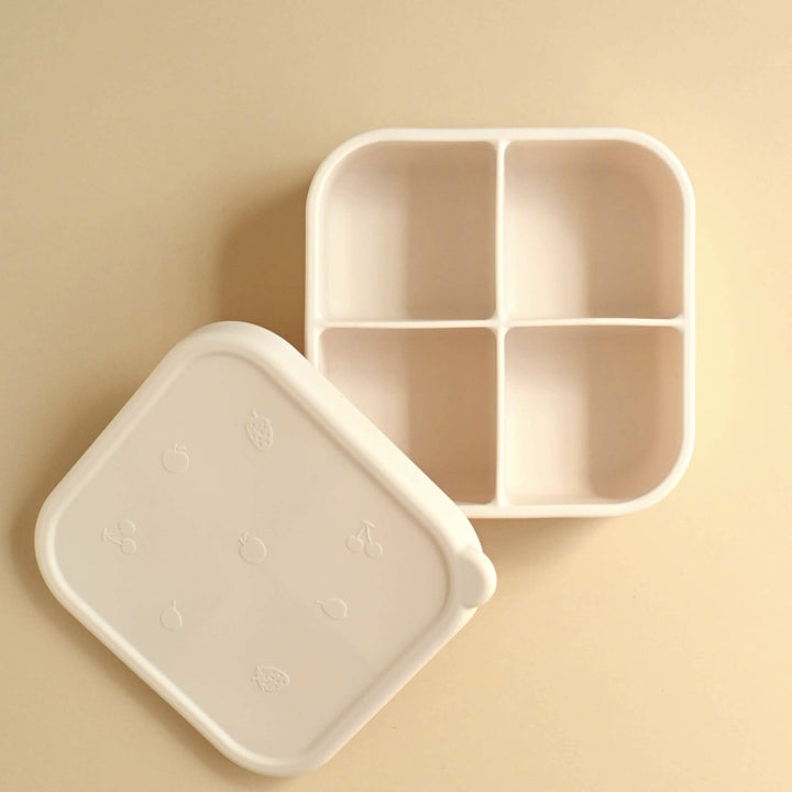 Beige compartmentalized food container with lid on a beige background