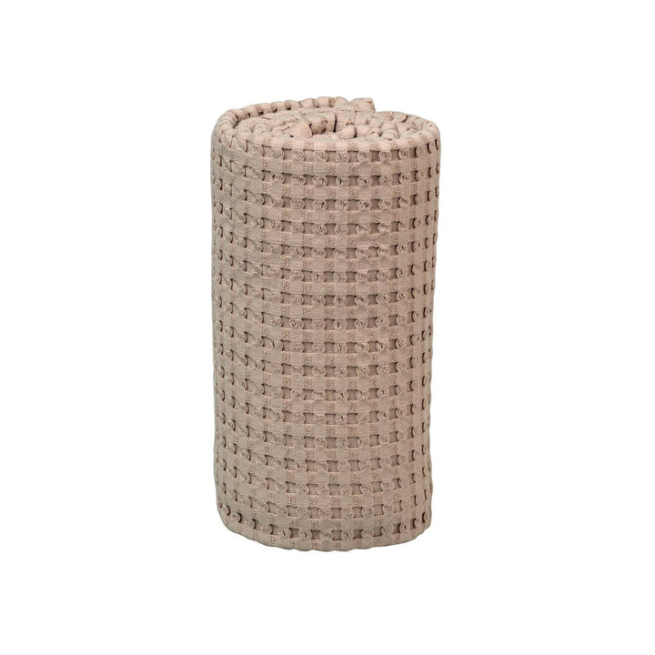 A rolled-up beige woven bath mat with a textured waffle pattern, shown on a plain white background.