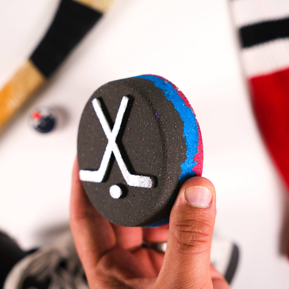 Bath bomb shaped like a hockey puck with a shoe charm inside, from Happy Hippo Bath, part of their bath bombs and salts collection.
