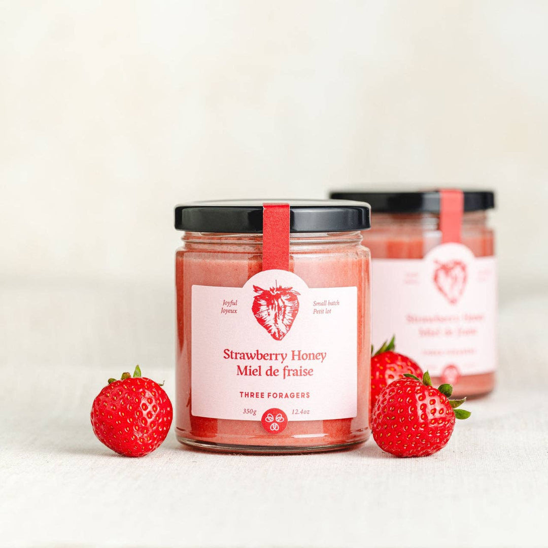Jar of strawberry-infused honey from Three Foragers, 350g, showcasing fresh strawberries and golden honey in a clear glass jar
