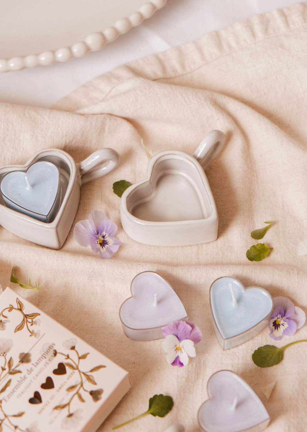 Heart-shaped ceramic containers with small flowers on a soft fabric background