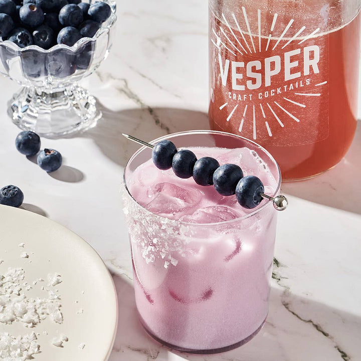 Vesper Craft Cocktails Blueberry Coconut Margarita mixer in a clear bottle with a colorful label, ready for cocktail making.