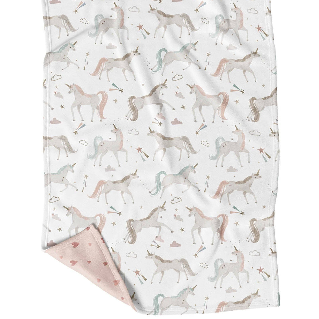 Unicorn patterned blanket with pink corner on a white background