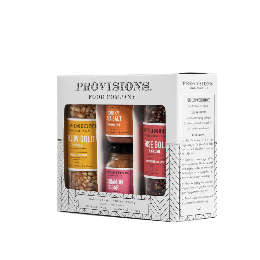Provisions Food Company 'First From Here' gift set in a white box with a geometric pattern, featuring jars of popcorn, spices, and tea visible through a clear window.