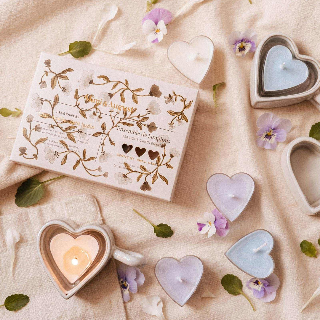 Heart-shaped candles and packaging on a soft fabric background with flowers.