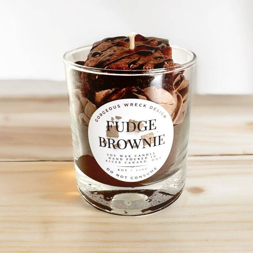 Fudge brownie candle in a glass jar with a label on a wooden surface