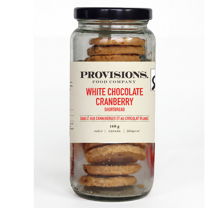 A glass jar of Provisions Food Company White Chocolate Cranberry Shortbread with a black lid and cream-colored label, set against a plain white background.