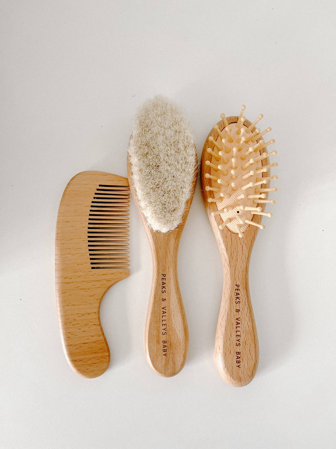 Set of three wooden hairbrushes on a light gray background