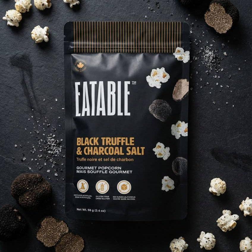 Eatable Black Truffle & Charcoal Salt popcorn package on a dark surface with truffles and popcorn.