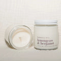 Candle and jar labeled 'lemongrass & bergamot' on a light background
