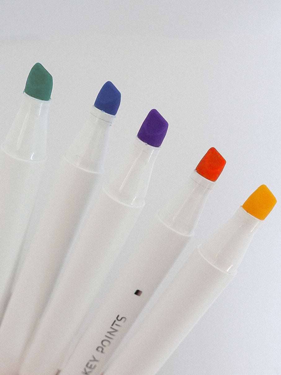 Five markers with colored caps on a white background