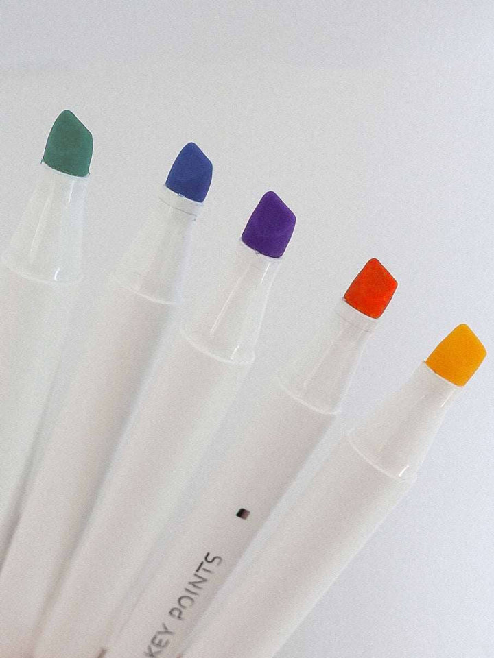 Five markers with colored caps on a white background