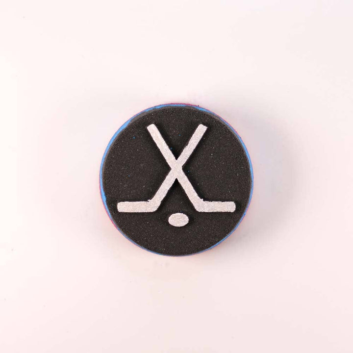 Happy Hippo Bath hockey puck bath bomb with a shoe charm, featuring orange and green colors and textured surface.