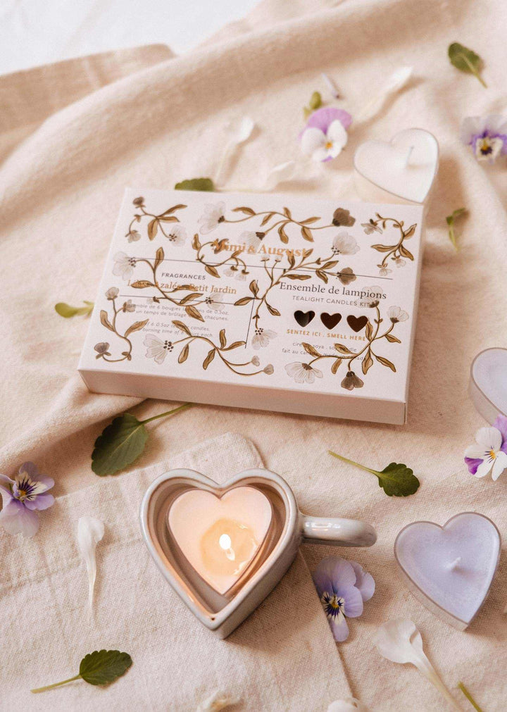 Decorative wooden block with cut-out hearts, a small heart-shaped candle, and flowers on a soft fabric background.