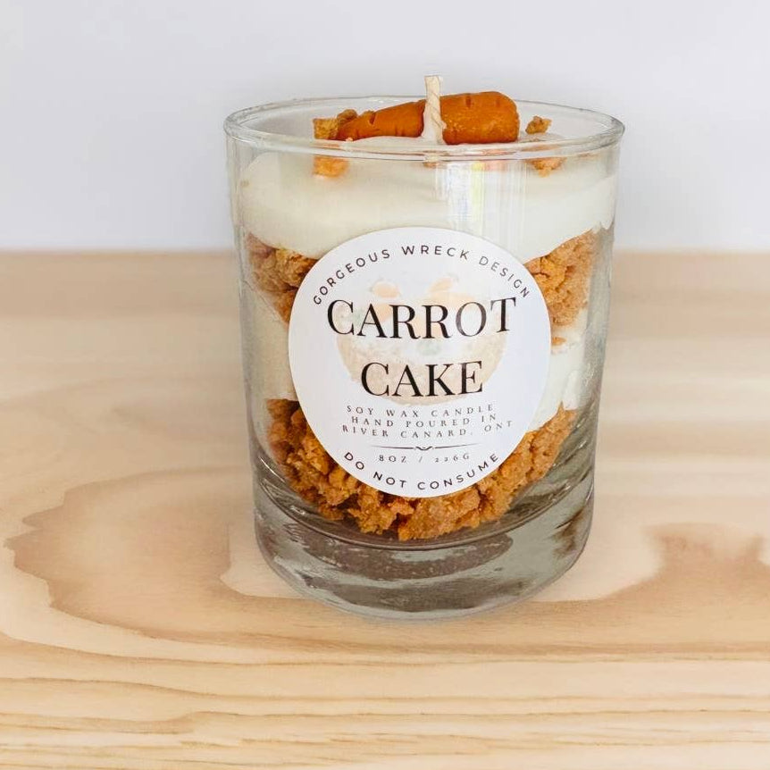 Carrot cake candle in a glass jar on a wooden surface with a white background
