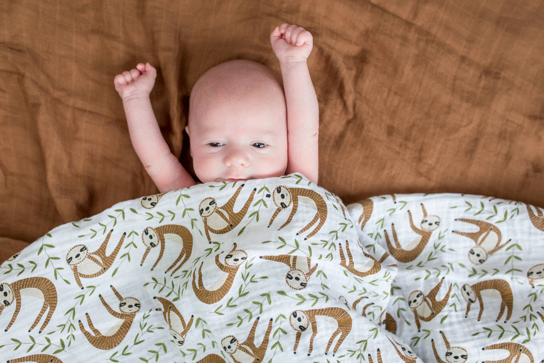 Soft Lulujo Baby Muslin Cotton Swaddle Blanket featuring a cute sloth design, ideal for newborns and infants.