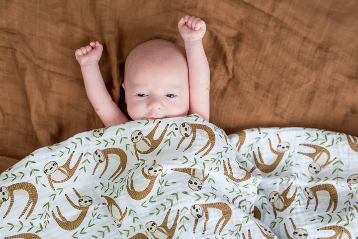 Soft Lulujo Baby Muslin Cotton Swaddle Blanket featuring a cute sloth design, ideal for newborns and infants.