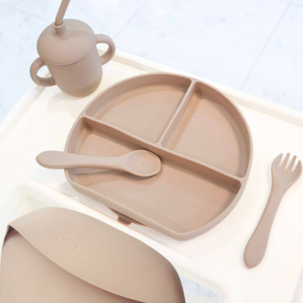 Beige children's dining set with plate, cup, spoon, and fork on a light background