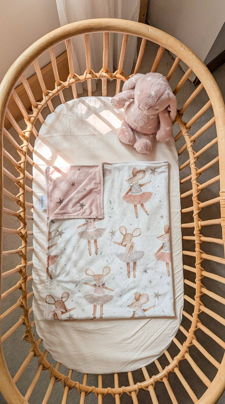 Baby crib with a quilt featuring animal patterns and a pink elephant toy.