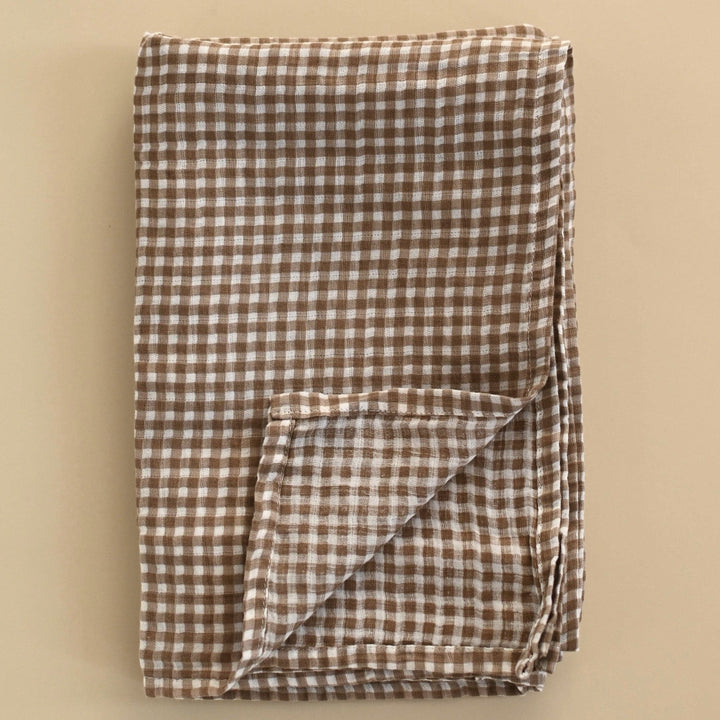 Folded brown and white checkered fabric on a beige background
