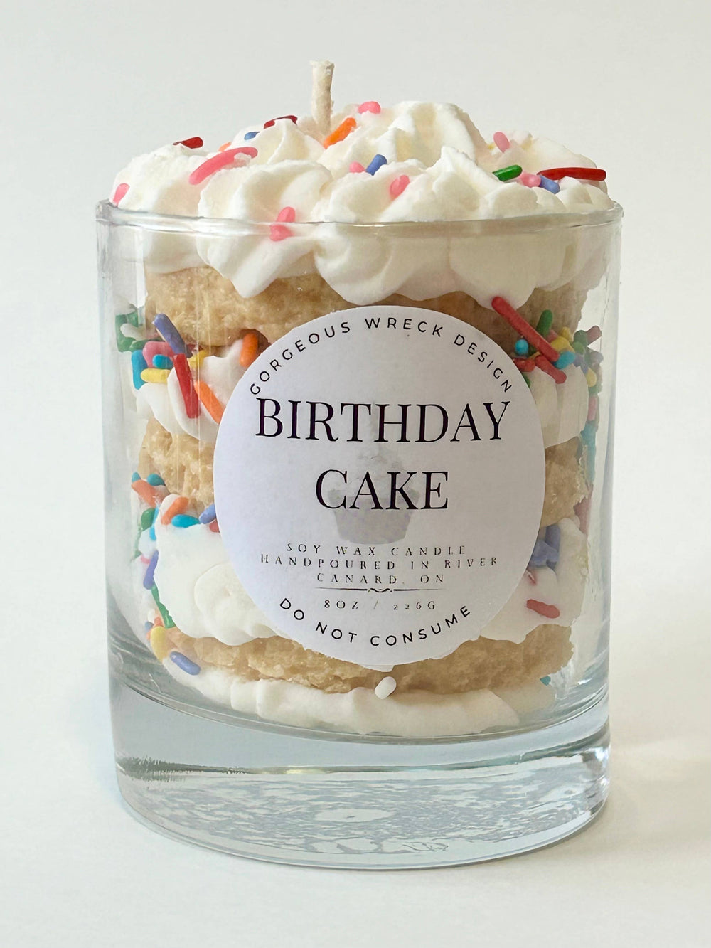 Birthday cake-themed candle with decorative elements on a white background