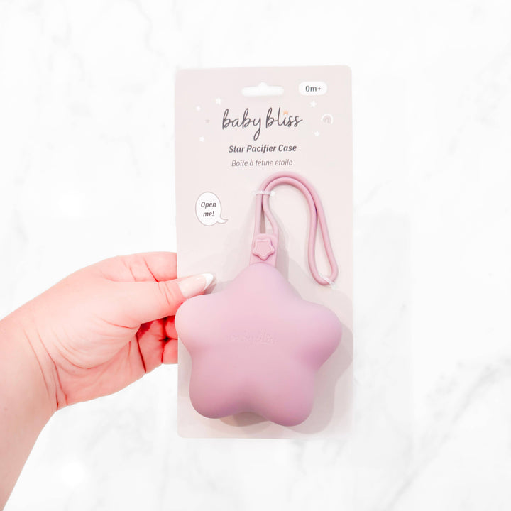Pink star-shaped pacifier case in packaging held by a hand on a white background