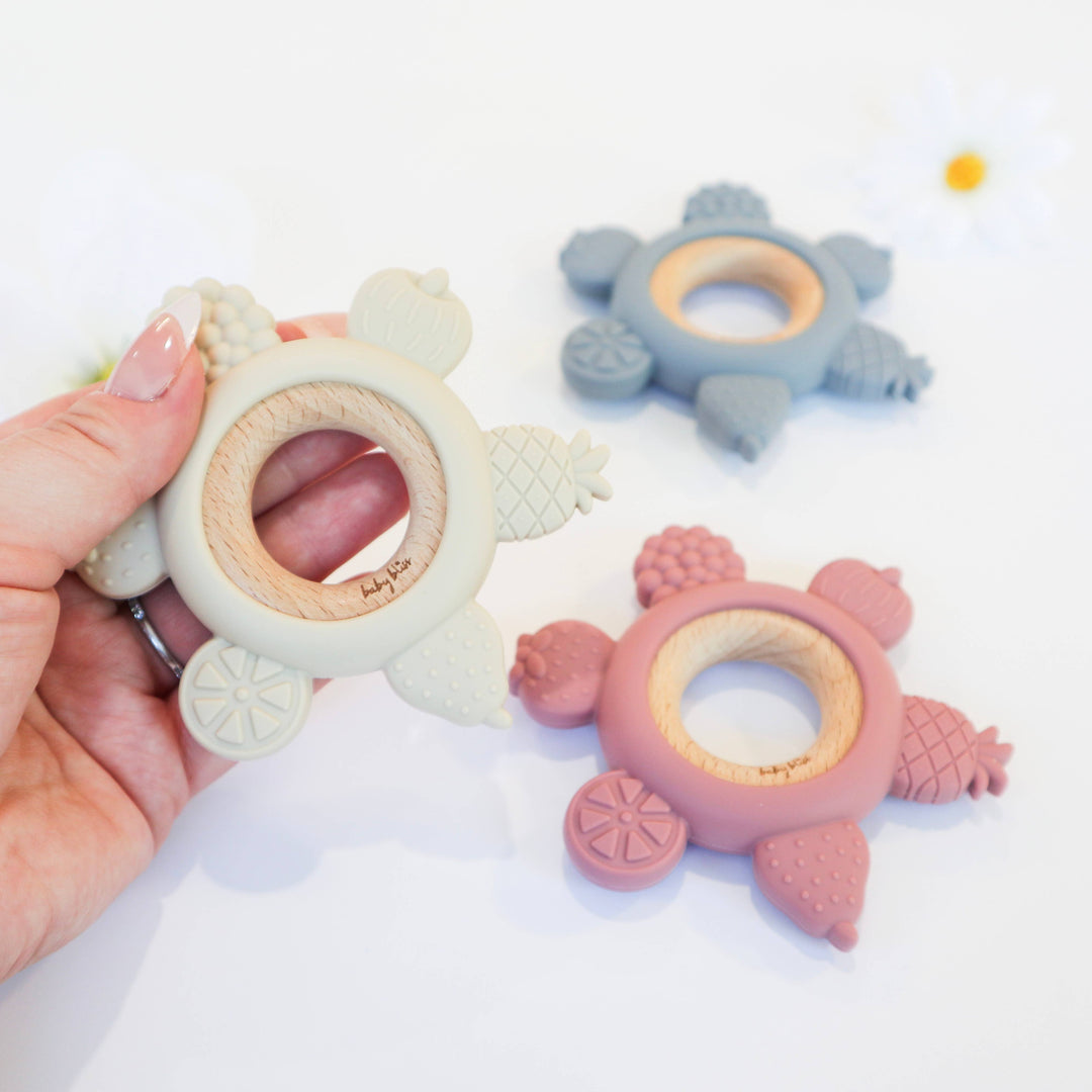 Baby teething ring with a hand holding it on a white background