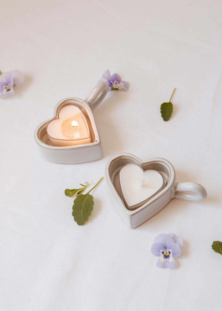Heart-shaped candle holders with candles on a white background