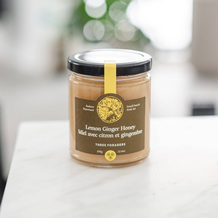 Jar of Lemon Ginger Infused Honey by Three Foragers, 350g, showcasing a golden honey with lemon and ginger pieces.