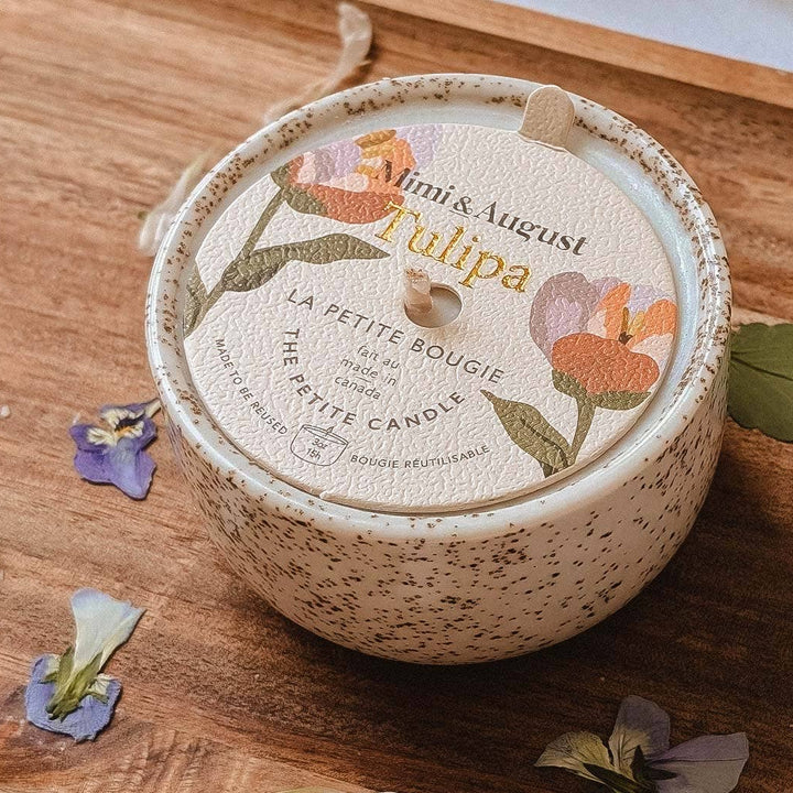 Small round container with floral design on a wooden tray with dried flowers and leaves.