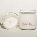 Two candles, one lit and one unlit, with 'London Fog' branding on a light background.