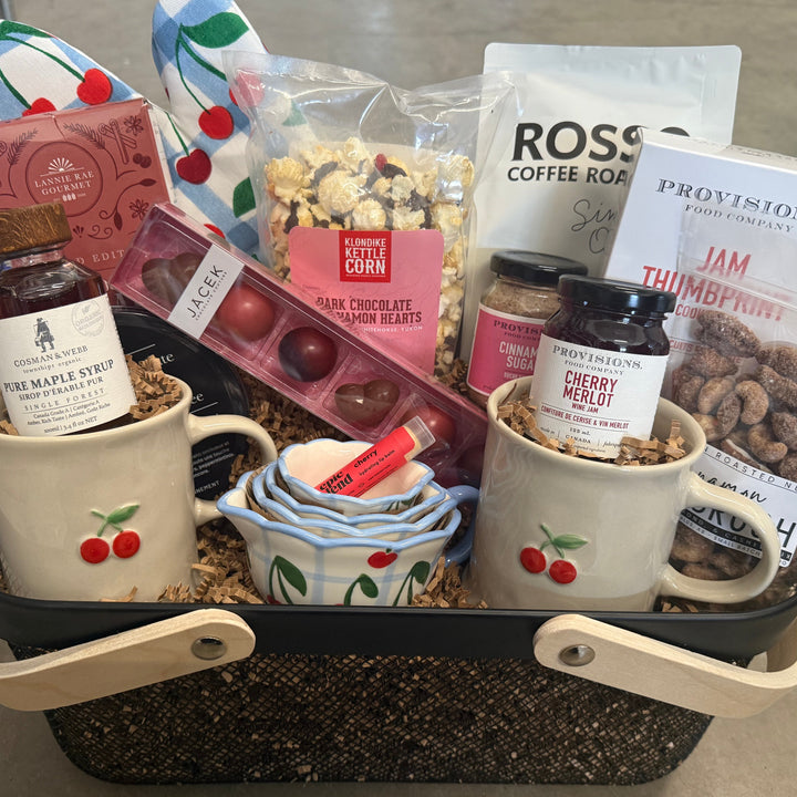 Gift basket with mugs, snacks, and coffee on a concrete floor