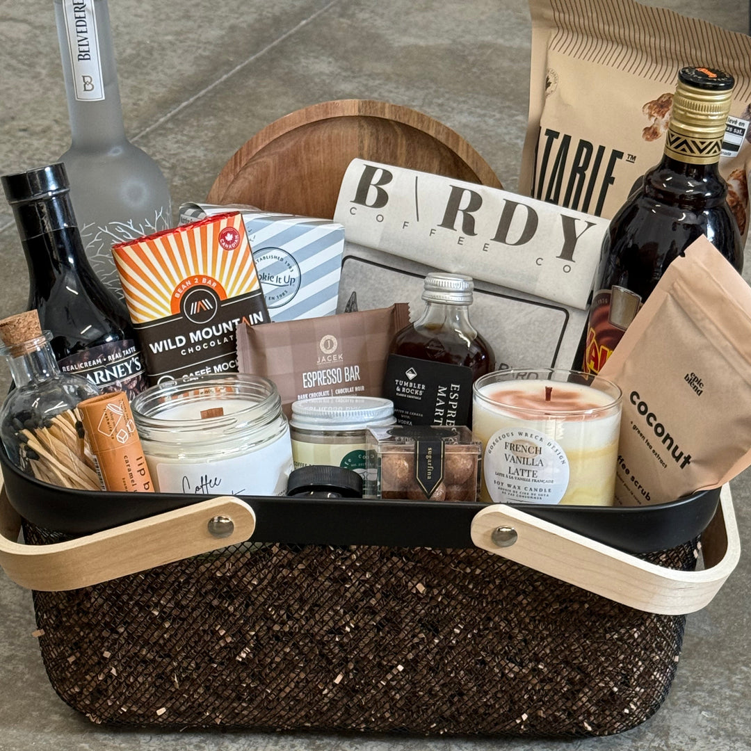Open suitcase with travel items including bottles, a candle, and a newspaper on a concrete surface.