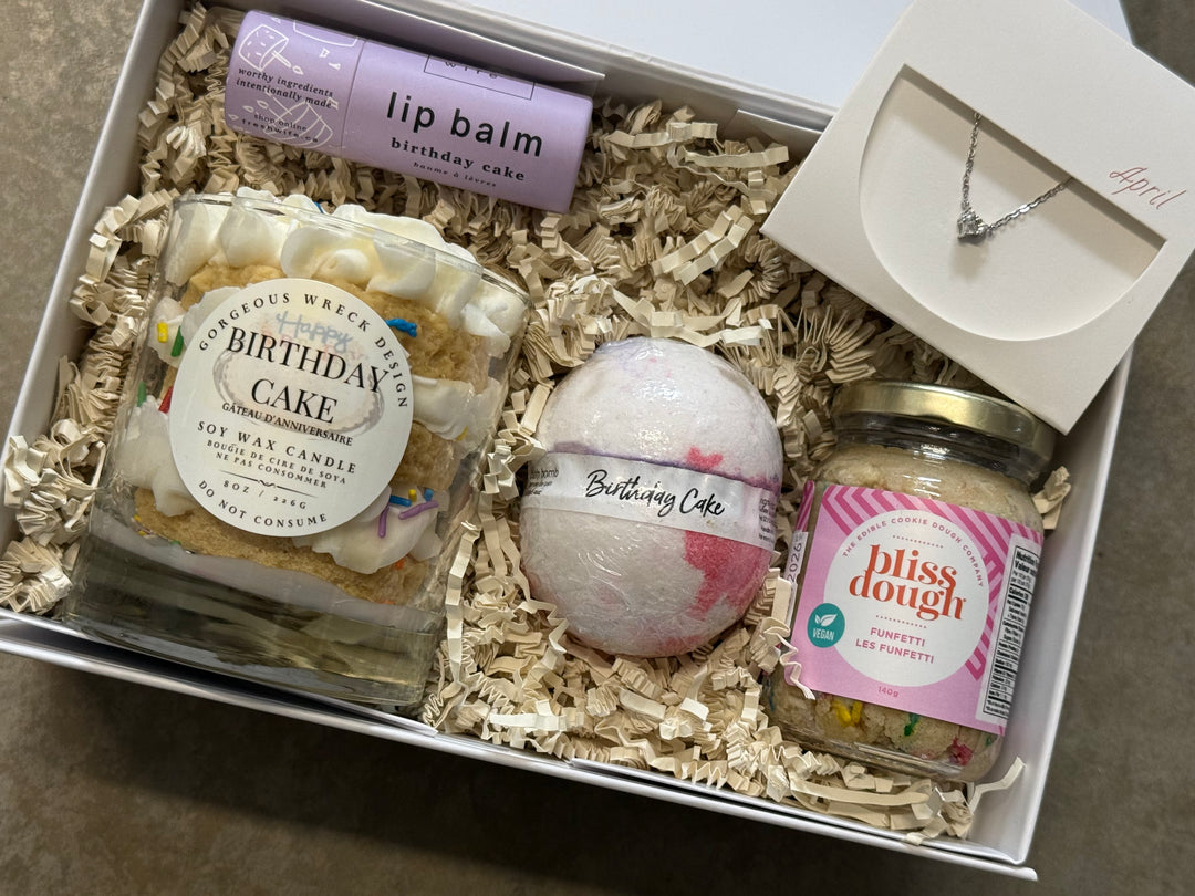 Gift set with 'Birthday Cake' themed products including a candle, bath bomb, lip balm, and pliss dough in a box.