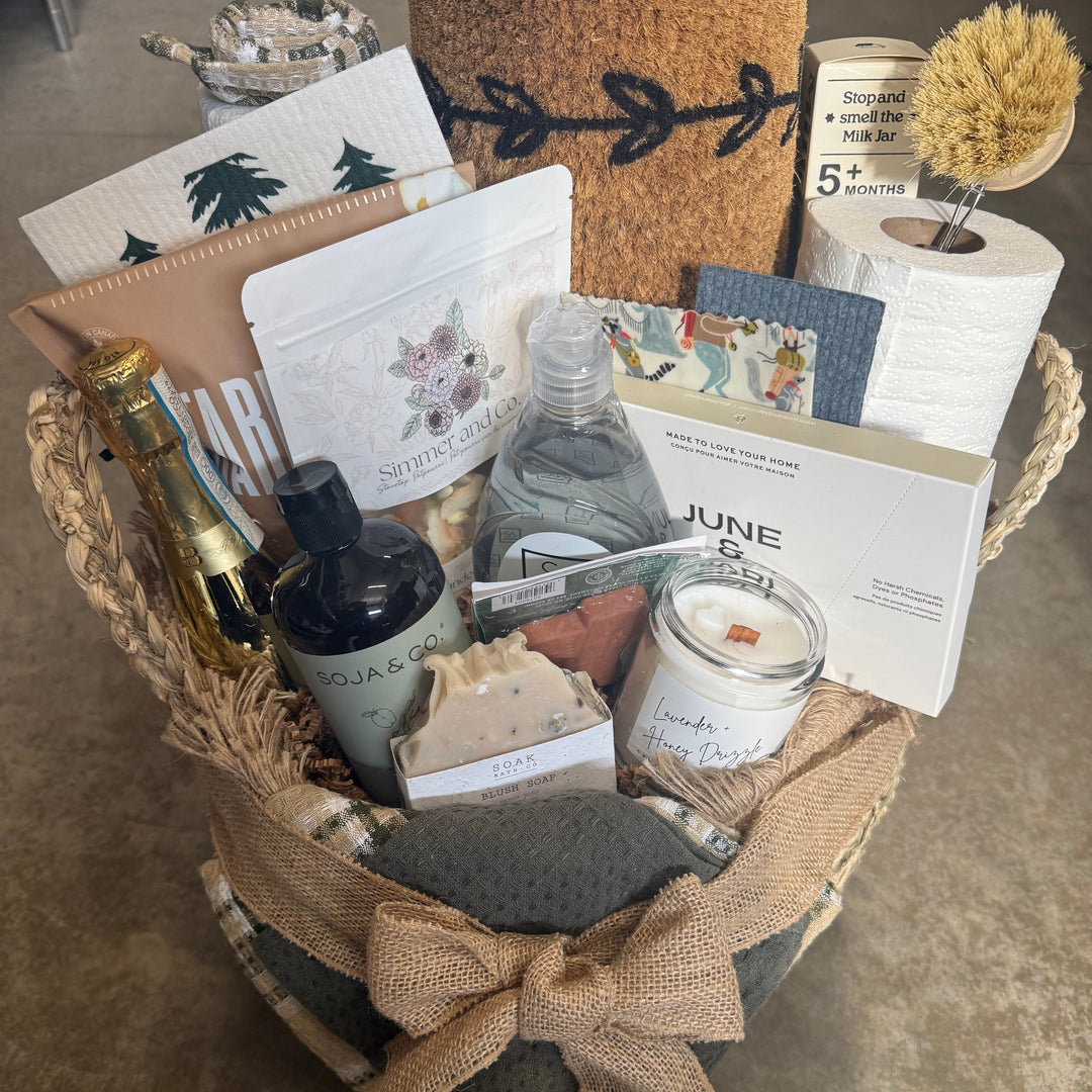 Decorative basket with candles, books, and stationery items on a textured surface