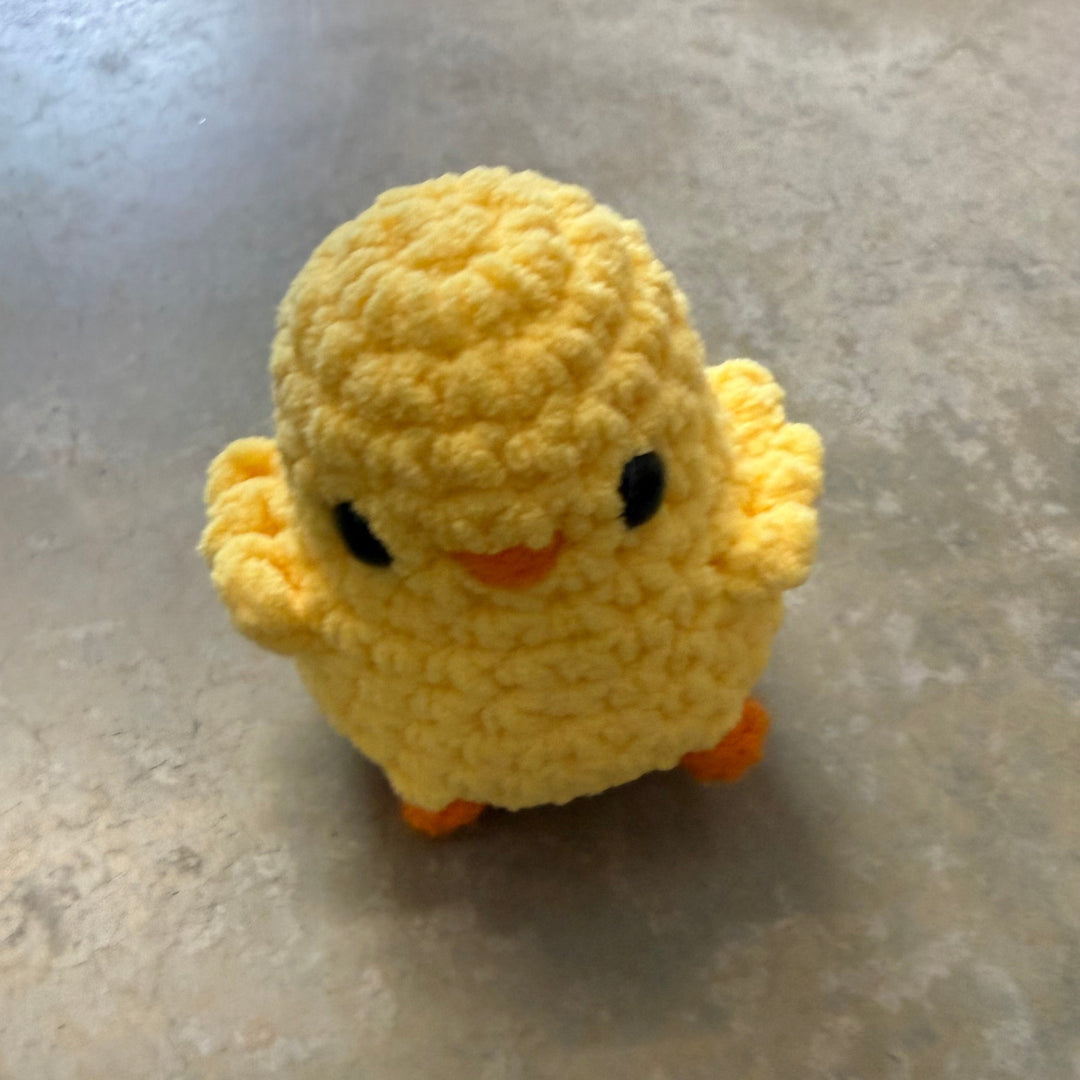 Small yellow crocheted duck toy on a gray surface
