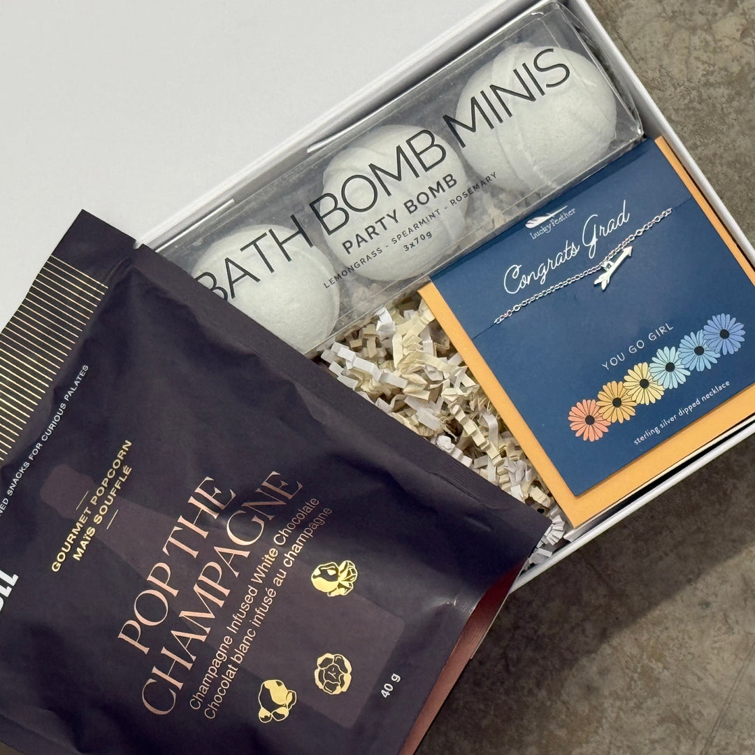 Gift set with bath bombs, champagne-themed packaging, and a card on a concrete surface.