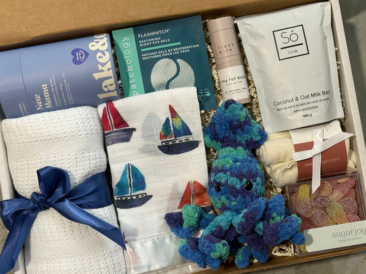 Gift box with baby items including socks, a plush toy, and bath products.