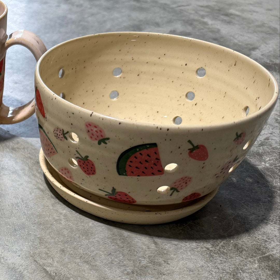 Four ceramic items including a mug, two mugs with floral patterns, and a decorative bowl on a gray surface.