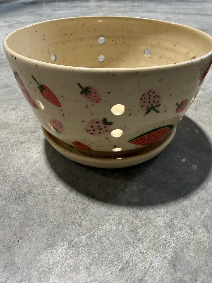 Ceramic pot with strawberry pattern on a gray surface