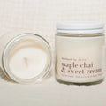 Two candles, one lit and one unlit, on a textured surface with 'maple chai & sweet cream' text.