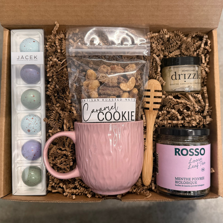 Gift box with a pink mug, cookies, and other items on a white background
