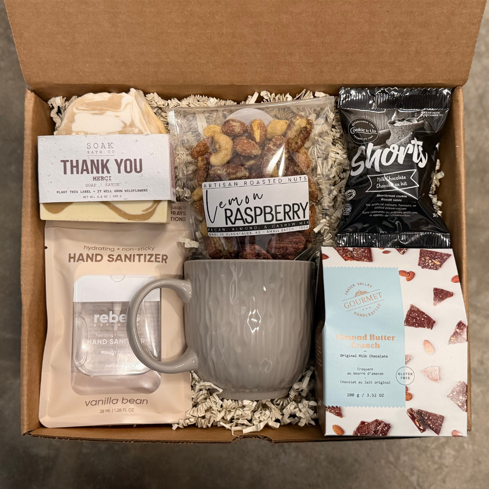 Gift box with a mug, snacks, and other items on a brown background