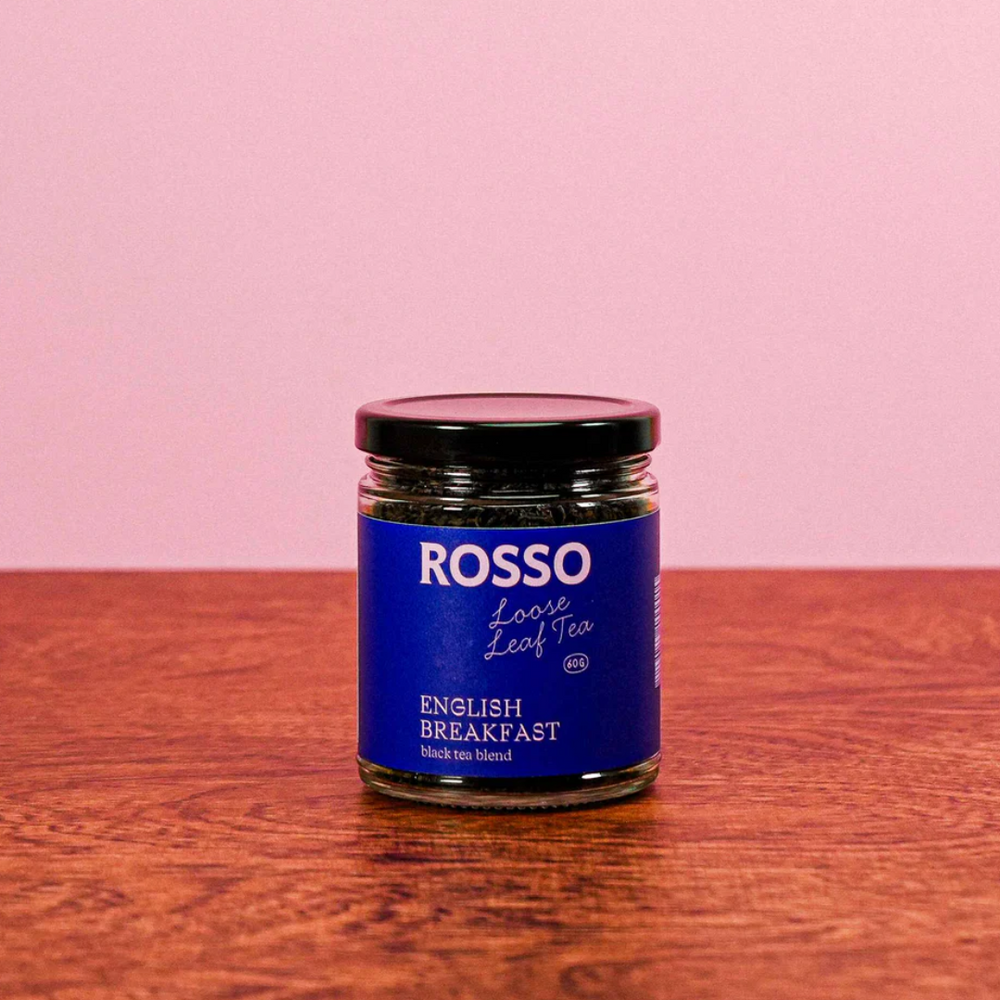 Jar of Rosso English Breakfast tea on a wooden surface with a pink background