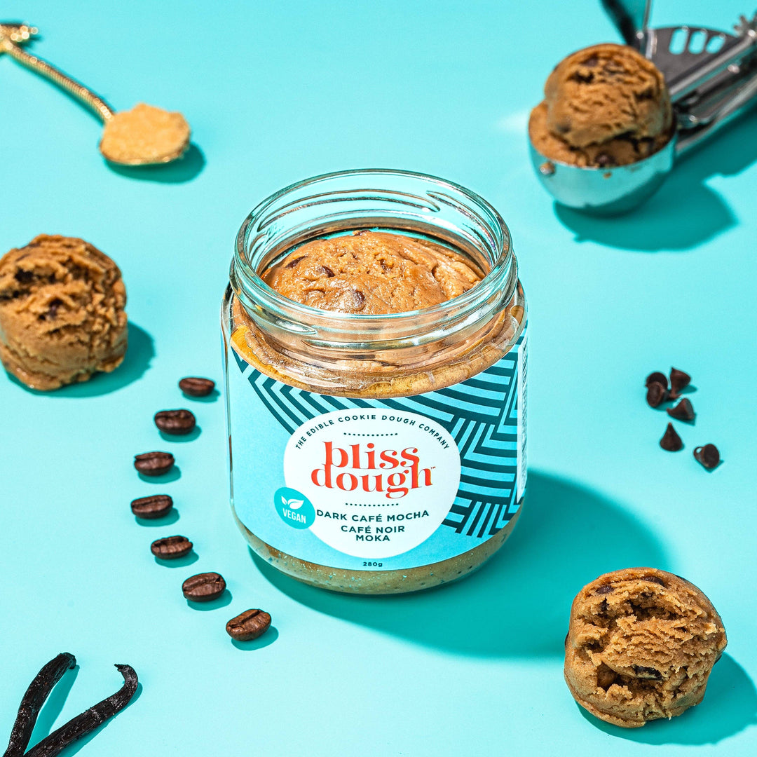 Jar of 'bliss dough' cookie dough cream with cookies and coffee beans on a blue background