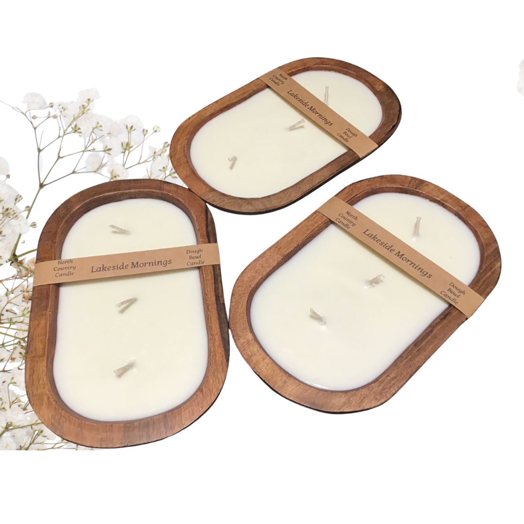 Three oval soy candles in wooden holders with paper bands reading &