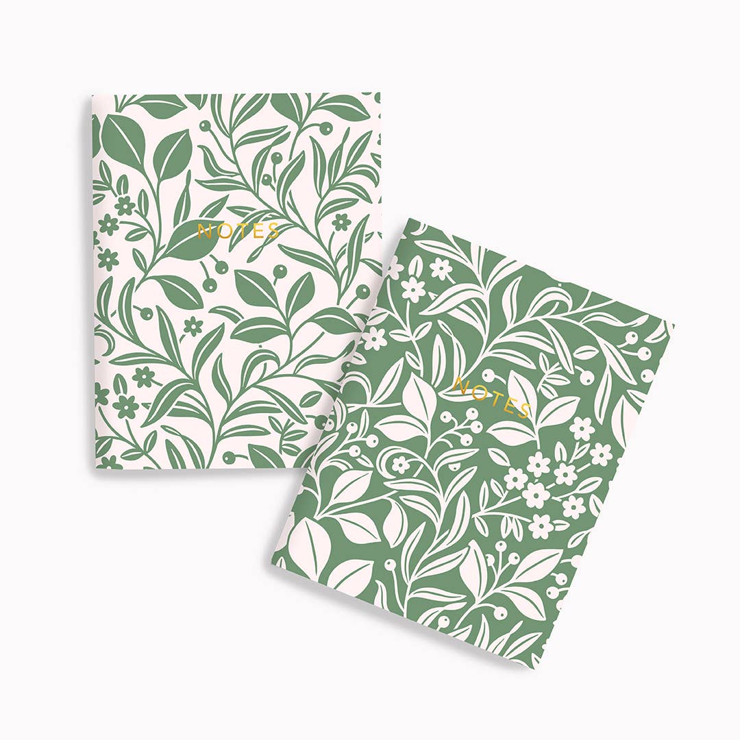 Two green notebooks with floral patterns on a white background