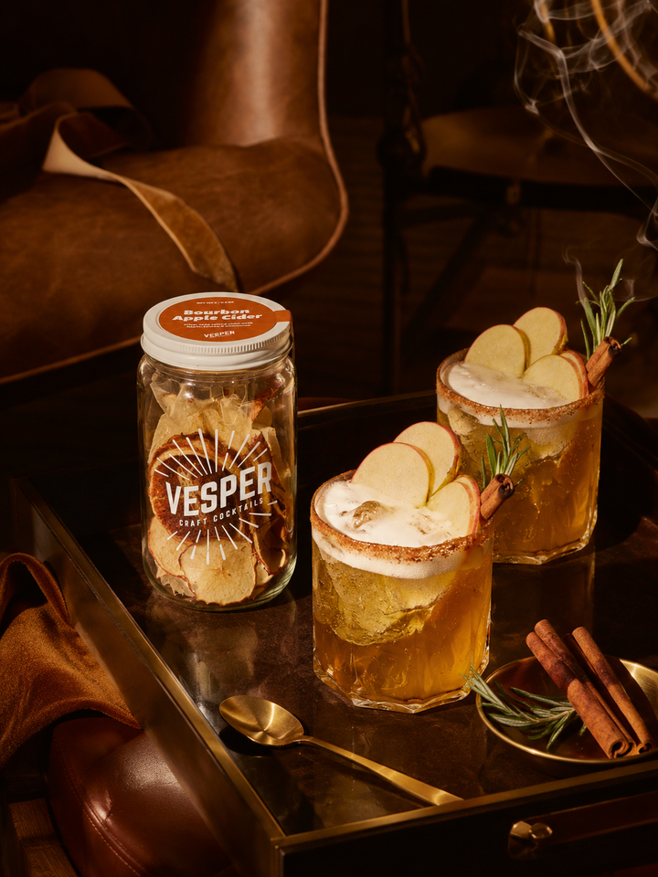 Vesper cocktail jar with two cocktails on a tray, garnished with cinnamon and rosemary.
