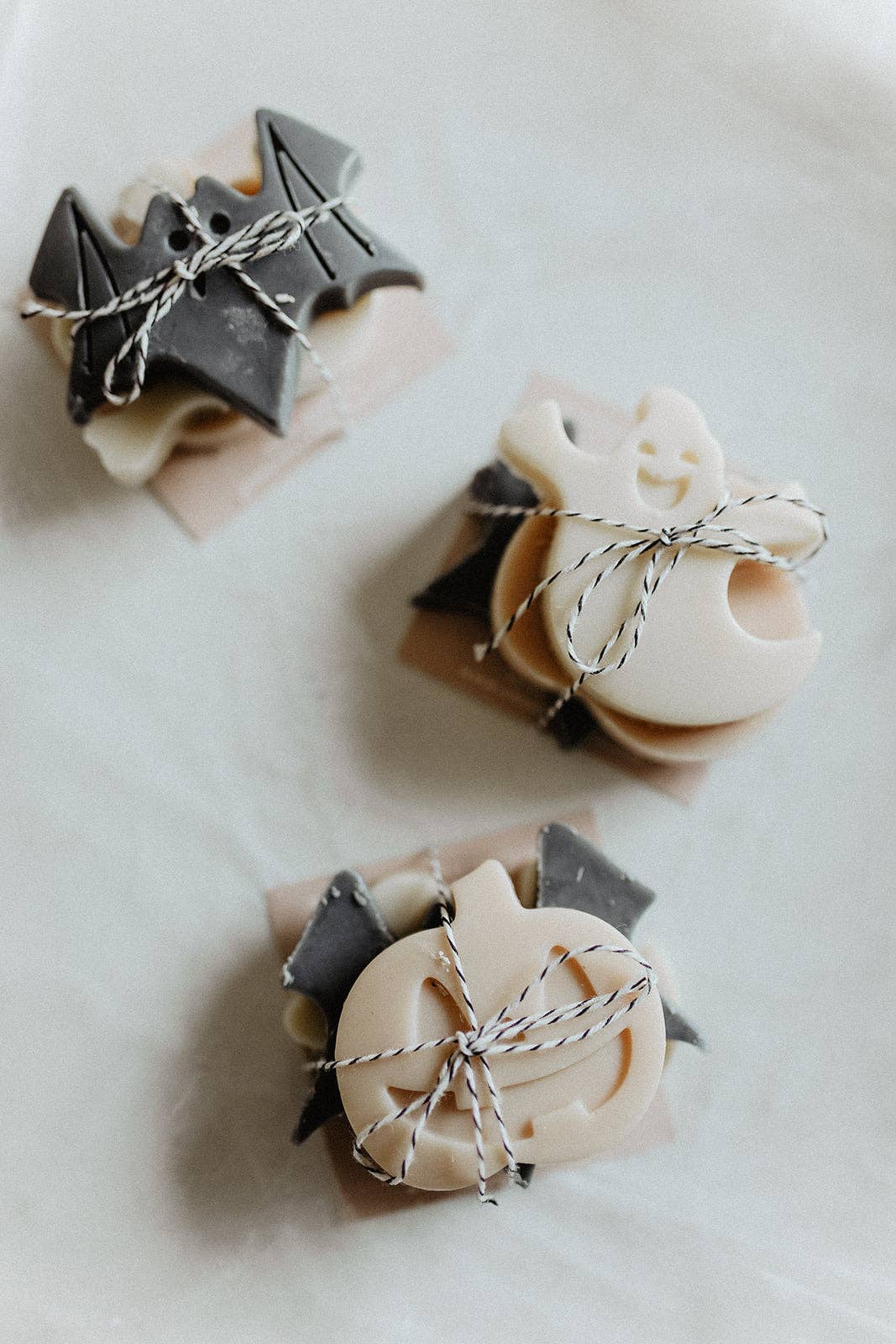 Three small soap bars shaped like ghosts and bats on a white background